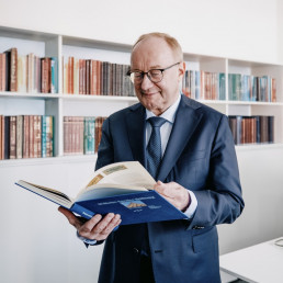 Mann im Anzug liest Buch in einem Büroraum