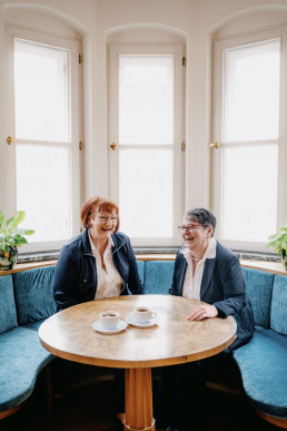 Zwei Frauen im Gespräch bei Kaffee in heller Sitznische
