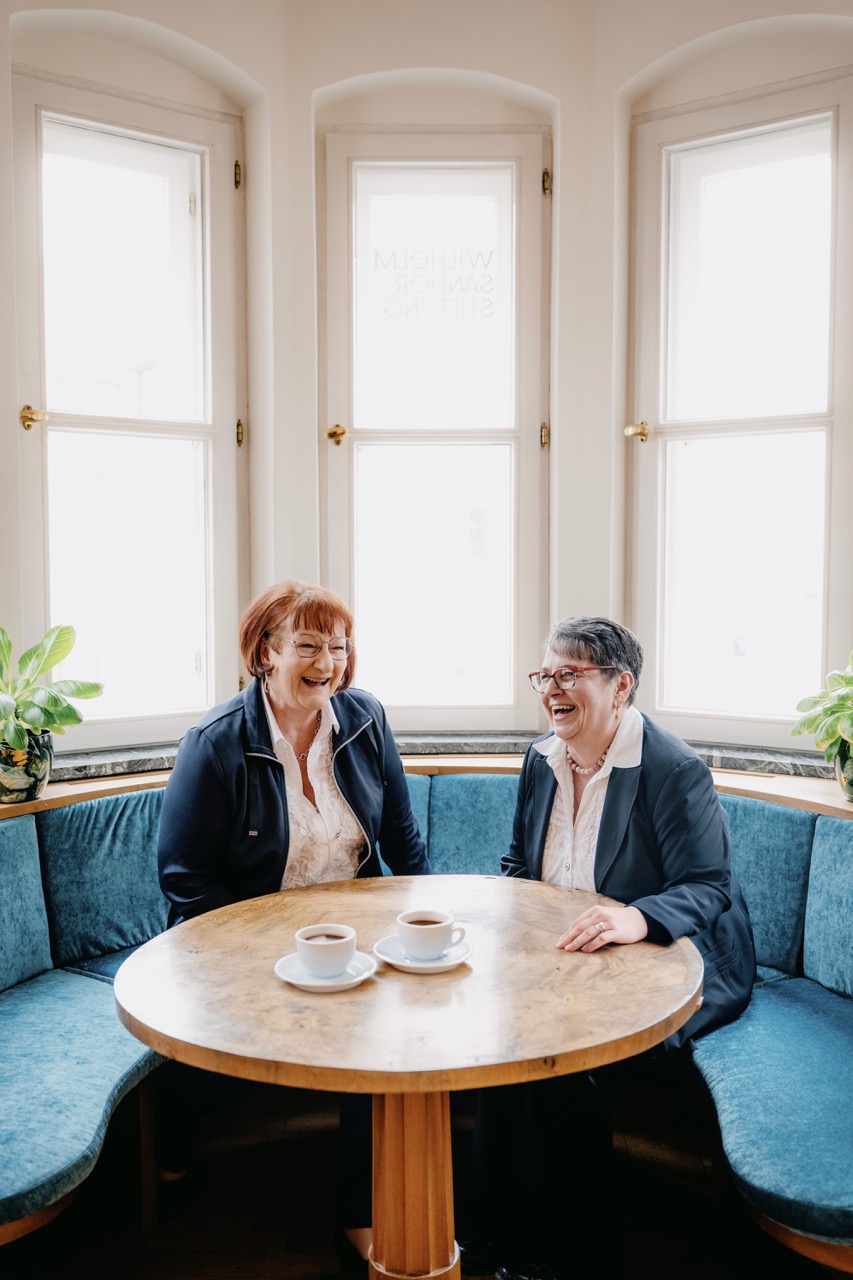 Zwei Frauen im Gespräch bei Kaffee in heller Sitznische