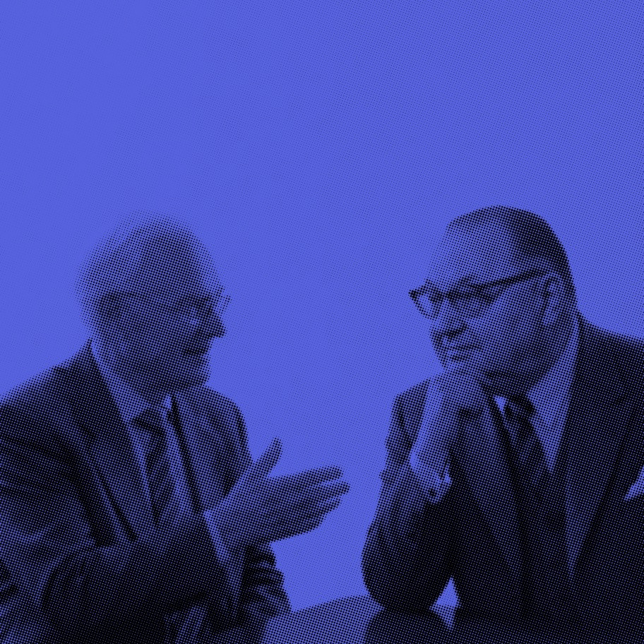 Jörg Koppenhöfer und Wilhelm Sander im Anzug im Gespräch an einem Tisch, künstlerisch in Blau dargestellt.